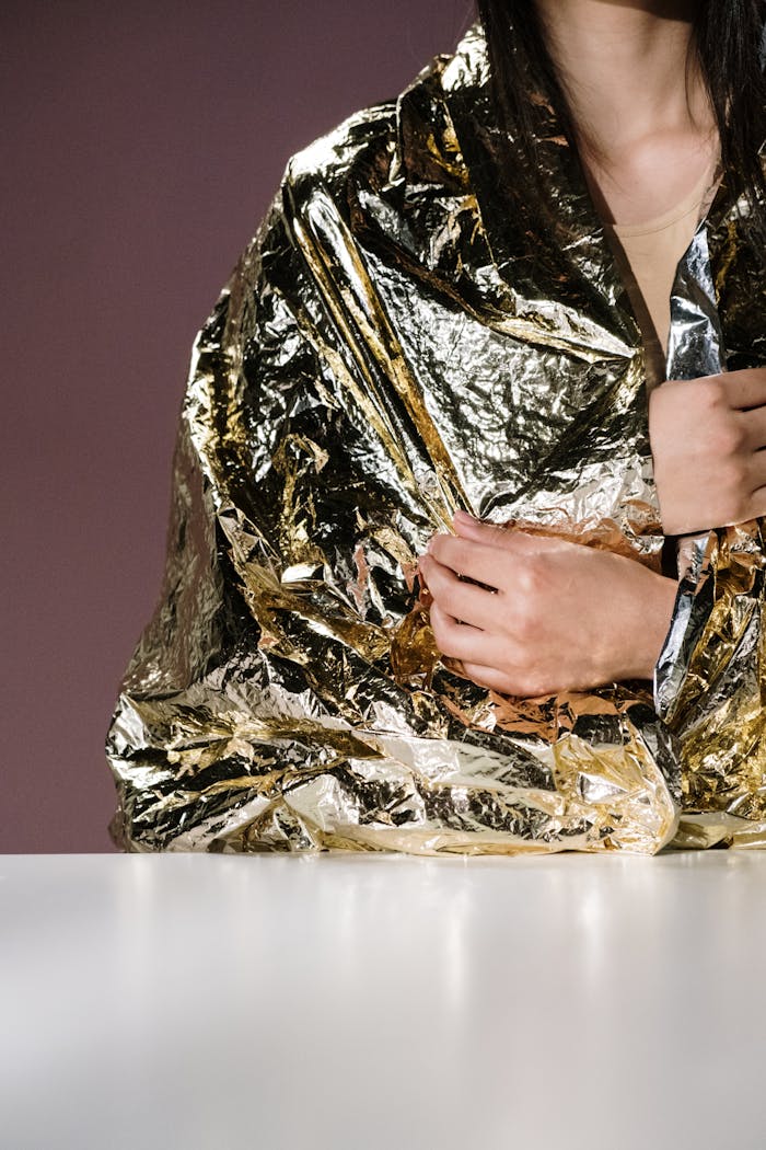 Close-up of a person wrapped in a reflective emergency blanket for warmth and protection.